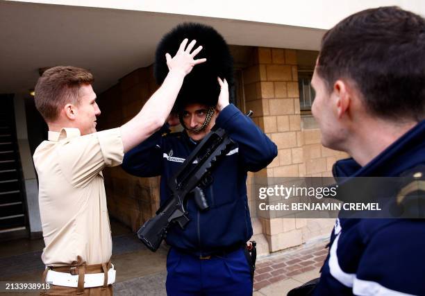 Member of France's Gendarmerie Garde Republicaine tries on the bearskin hat of a member of the British Army's F Company Scots Guards, following a...