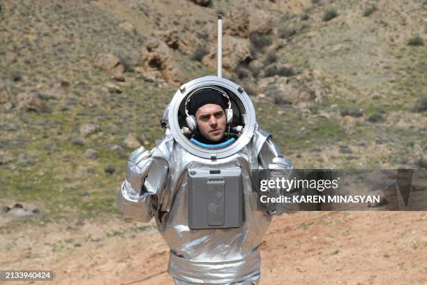 Member of the AMADEE-24 Mars Analog Research Mission wearing a spacesuit walks after leaving an isolation facility at the "Mars station", a simulated...