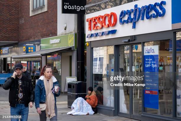Person sitting on the pavement outside Tesco Express underneath a sleeping bag on 2nd April 2024 in Gloucester, United Kingdom. Gloucester city...