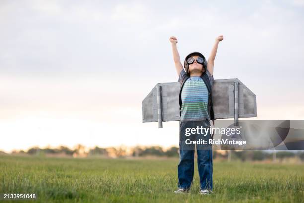niño joven con mochila propulsora en campo de hierba - imaginación fotografías e imágenes de stock