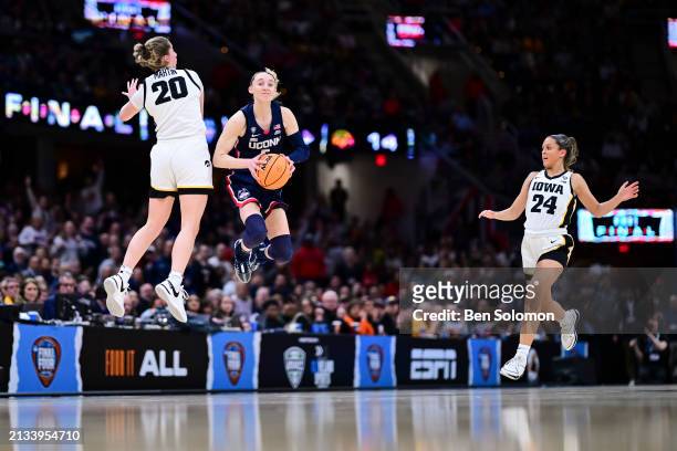 Kate Martin of the Iowa Hawkeyes jumps to defend a shot by Paige Bueckers of the UConn Huskies during the NCAA Women's Basketball Tournament Final...
