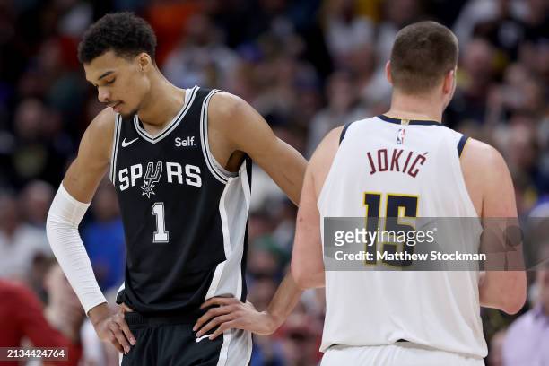 Victor Wembanyama of the San Antonio Spurs and Nikola Jokic of the Denver Nuggets pass on the court during the fourth quarter at Ball Arena on April...