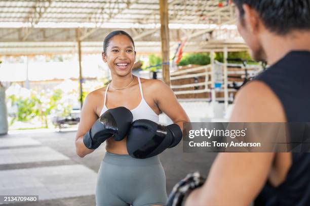 young woman boxer working out with trainer - kickboxen stock-fotos und bilder