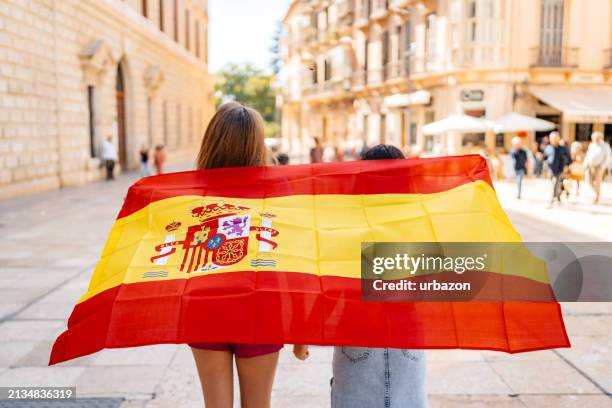 deux amies agitant un drapeau espagnol dans la rue à malaga en espagne - malaga photos et images de collection