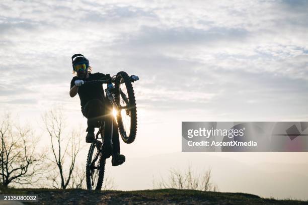 male mountain biker pops a wheelie - wheelie stock pictures, royalty-free photos & images