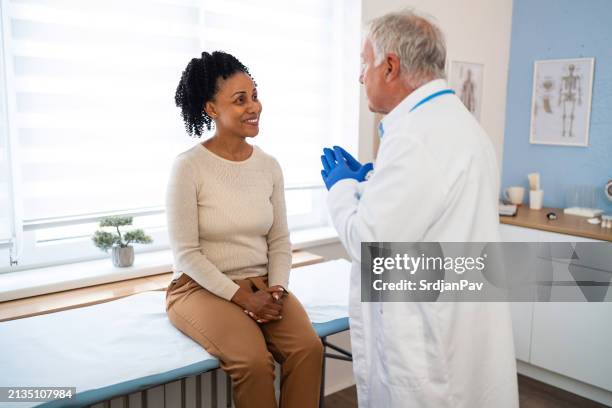 en el momento de la ordenación, una mujer adulta mediana de etnia negra que se somete a un chequeo médico anual con un médico caucásico de alto rango - acontecimiento anual fotografías e imágenes de stock