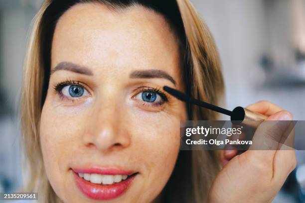 mature middle-aged woman applying eyelash makeup, close-up - eye make up stock pictures, royalty-free photos & images