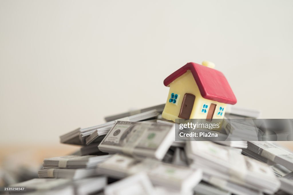 House on stack US dollar banknotes with white wall background copy space.