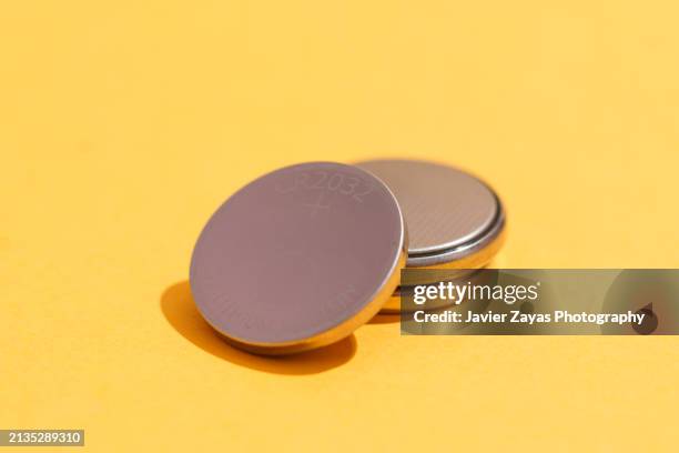 used cr2032 lithium button cell batteries isolated on yellow - knöpfen stock-fotos und bilder