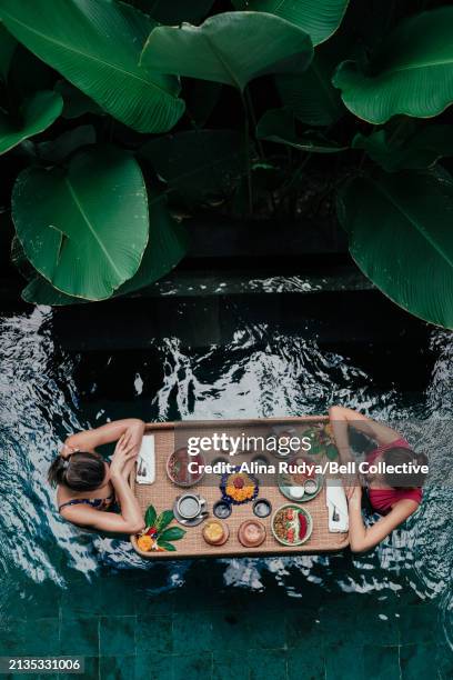 two women having a floating breakfast in a pool - floating food stock pictures, royalty-free photos & images