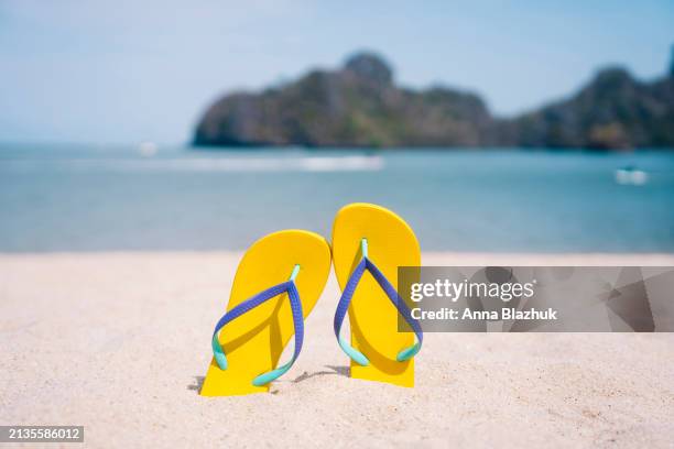yellow flip-flops on white sand beach by blue sea. bright sunlight. - ciabatta infradito foto e immagini stock