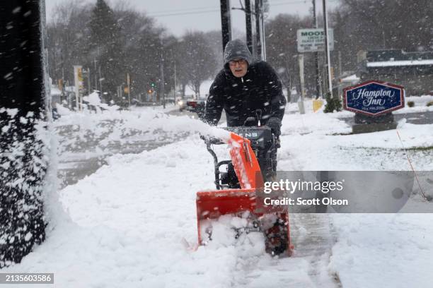 Worker clears snow from a sidewalk near Lambeau Field on April 03, 2024 in Green Bay, Wisconsin. A heavy, wet snow is being dumped on much of...