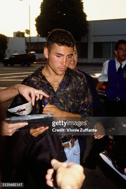 Mexican-American boxer Oscar De La Hoya among a group of people signs autographs as he attends a boxing program at the Great Western Forum in...
