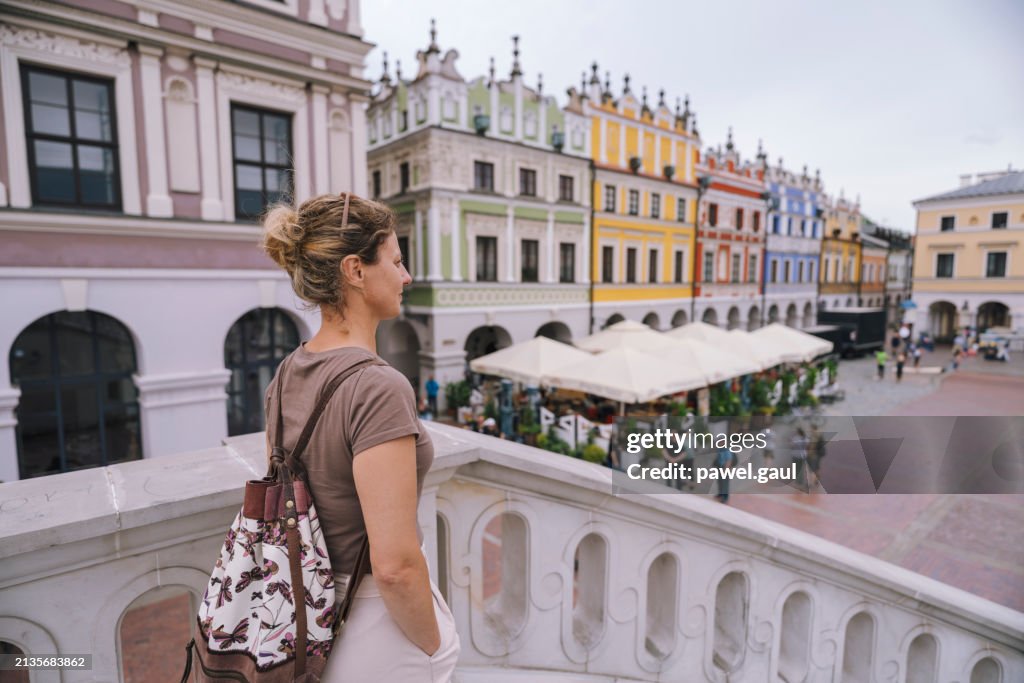 Femme regardant la place rynek dans la ville de Zamosc en Pologne