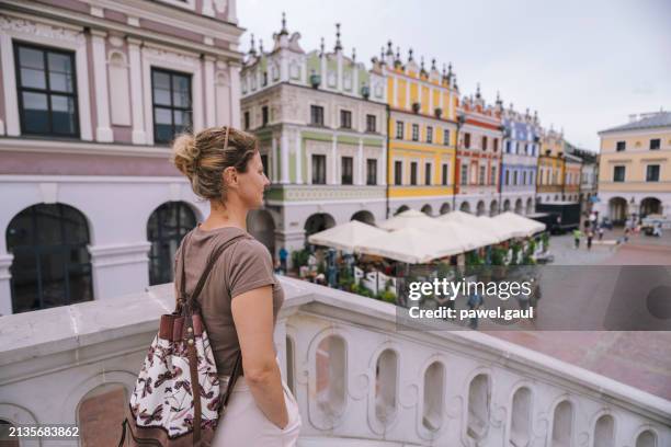 woman looking at rynek square in zamosc city poland - marktplein stockfoto's en -beelden