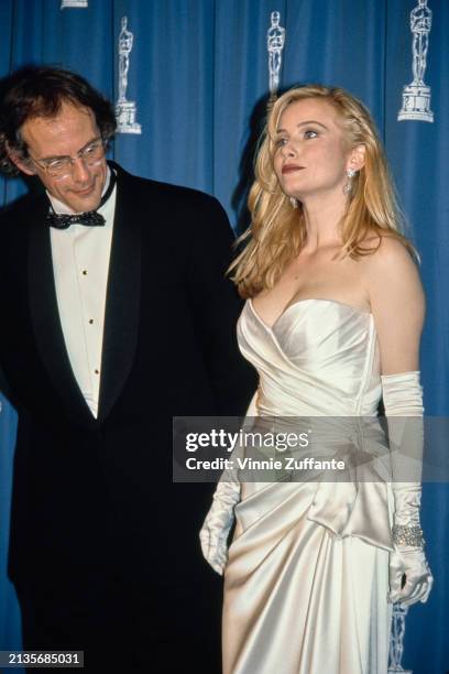 American actor Christopher Lloyd, wearing a tuxedo and bow tie, and American actress Rebecca De Mornay, who wears a strapless white evening gown with...