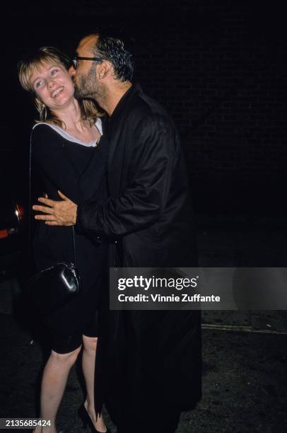 American actress Rebecca De Mornay, wearing a black dress with a white collar, kissed by her husband, American screenwriter and author Bruce Wagner,...