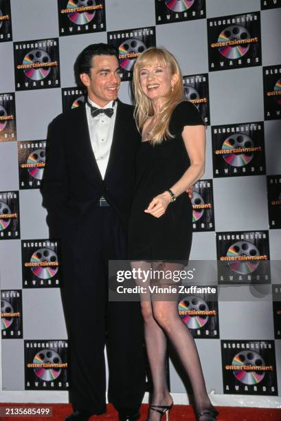 American actor Peter Gallagher, wearing a tuxedo and bow tie, and American actress Rebecca DeMornay, who wears a black minidress, in the inaugural...