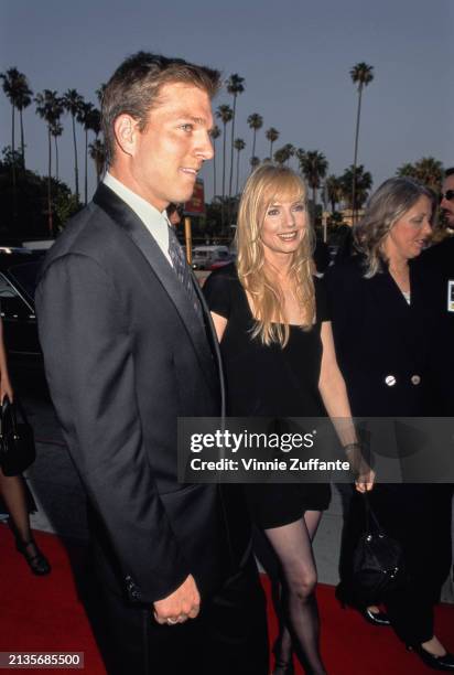 American sportscaster and actor Patrick O'Neal, wearing a black suit, and American actress Rebecca De Mornay, who wears a black minidress, attend the...