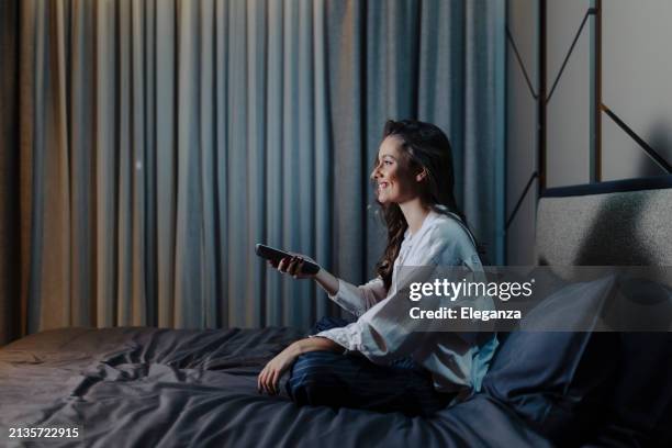 woman watching movie at bed at night - television movie stock pictures, royalty-free photos & images