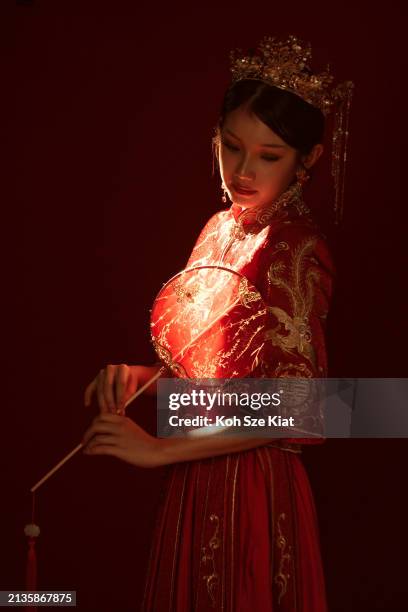 stunning backlit portrait of an asian chinese woman in traditional bridal tea dress holding a hand fan - rim light portrait stock pictures, royalty-free photos & images