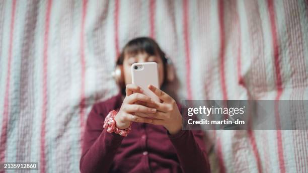 adolescente en la cama está escuchando música - malos hábitos fotografías e imágenes de stock