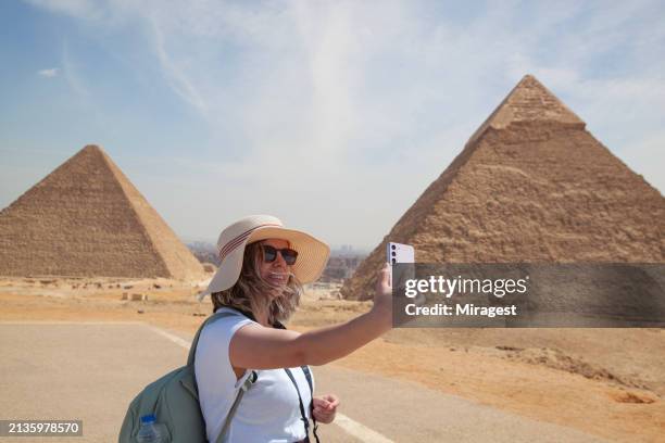 una mujer turista se toma una selfie de las pirámides de giza en el cairo, egipto. niña en el desierto del sahara. tiempo de los faraones. - forma piramidal fotografías e imágenes de stock