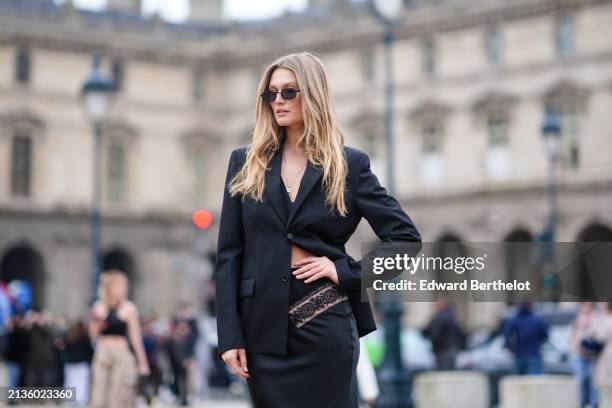 Toni Garrn wears a black blazer jacket, a black long skirt with floral embroidery details, sunglasses, outside Off-White, during the Womenswear...