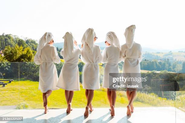 rückansicht von freundinnen in weißen bademänteln und handtüchern auf dem kopf, die auf dem balkon stehen - junggesellinnenabschied stock-fotos und bilder