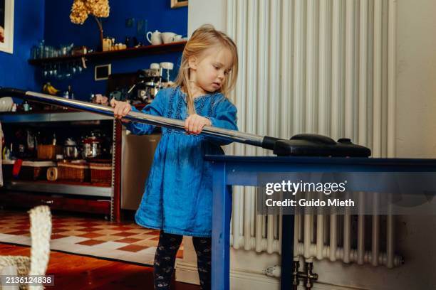 kid cleaning with vacuum cleaner a table at home. - staubsauger stock-fotos und bilder