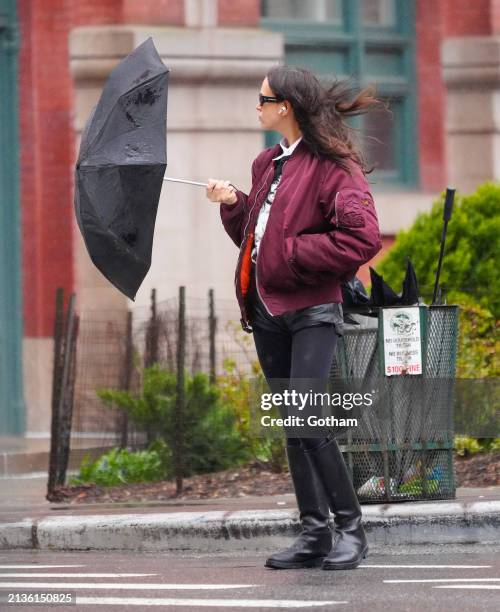 Irina Shayk is seen with her umbrella getting blown by the wind on April 03, 2024 in New York City.