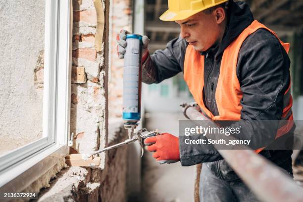 craftsman installing window in construction site - polyurethane stock pictures, royalty-free photos & images