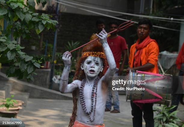 An Indian child dressed as the Hindu deity Shiva is dancing with others while begging for alms in Siliguri, India, on April 6 ahead of the 'Charak'...