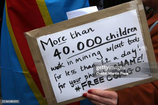 A protester holds a sign highlighting the cost to children used to mine minerals for the west during the demonstration on April 6, 2024 in London,...