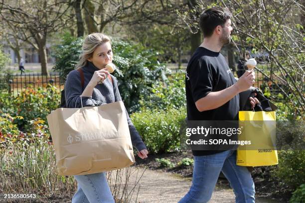Couple with ice cream walks at Hyde Park in London on a sunny spring day. Weather forecasters are expecting warmer temperature over the next few days.