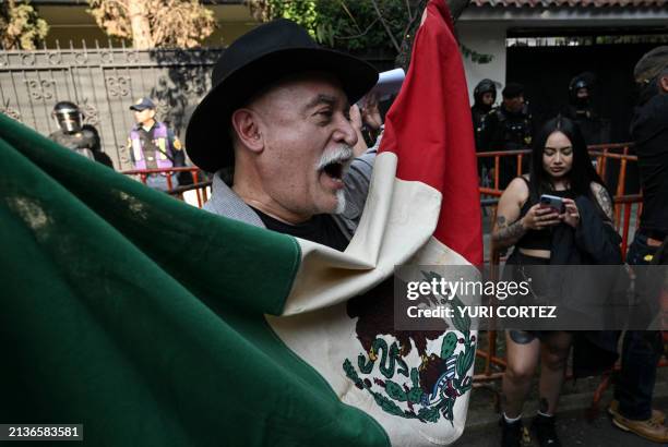 Man holding a Mexican flag protests outside the Ecuadorian embassy in Mexico City on April 6 following the severance of diplomatic relations between...