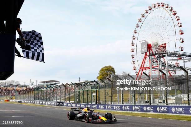 Race official waves the chequered flag as Red Bull Racing's Dutch driver Max Verstappen wins the Formula One Japanese Grand Prix race at the Suzuka...