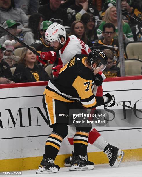 Michael Rasmussen of the Detroit Red Wings takes a hit from John Ludvig of the Pittsburgh Penguins in the second period during the game at PPG PAINTS...