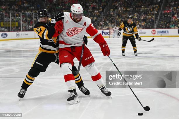 David Perron of the Detroit Red Wings skates with the puck against Bryan Rust of the Pittsburgh Penguins in the second period during the game at PPG...