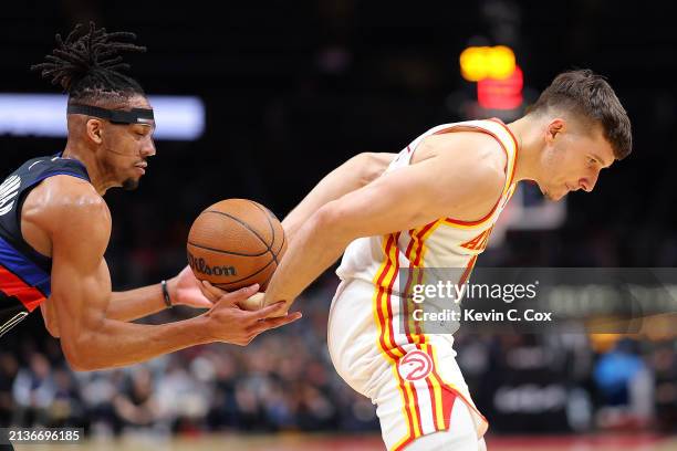 Bogdan Bogdanovic of the Atlanta Hawks nearly loses the ball as he dribbles it behind his back into the hands of Tosan Evbuomwan of the Detroit...