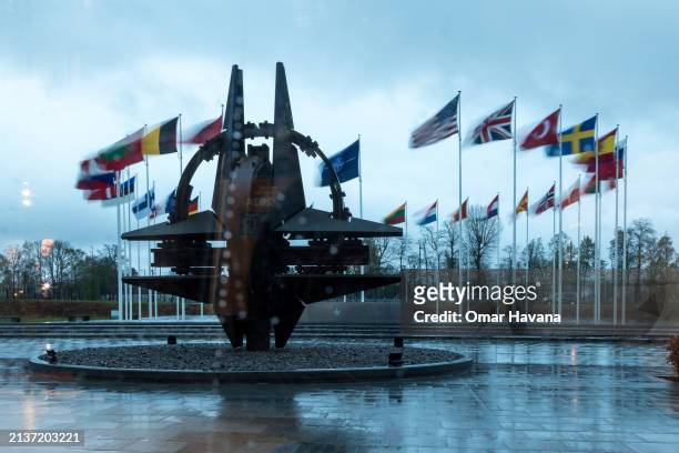 The NATO star is seen through a window with raindrops at NATO headquarters in front of the flags of the 32 member countries before the start of the...