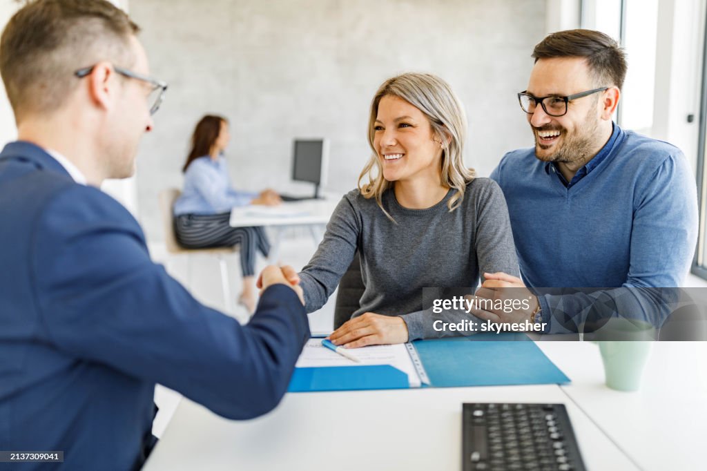 Happy couple came to an agreement with their financial advisor in the office.