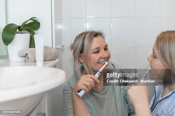shot of a woman and her daughter brushing their teeth at home - brushing stock pictures, royalty-free photos & images