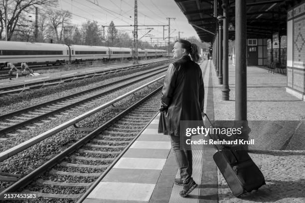 sideview of woman standing with luggage at railroad station platform - reinhard krull stock pictures, royalty-free photos & images