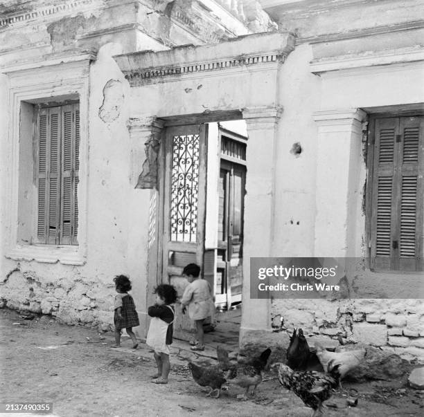 Children playing next to chickens outside a rundown villa in Athens, January 1949.