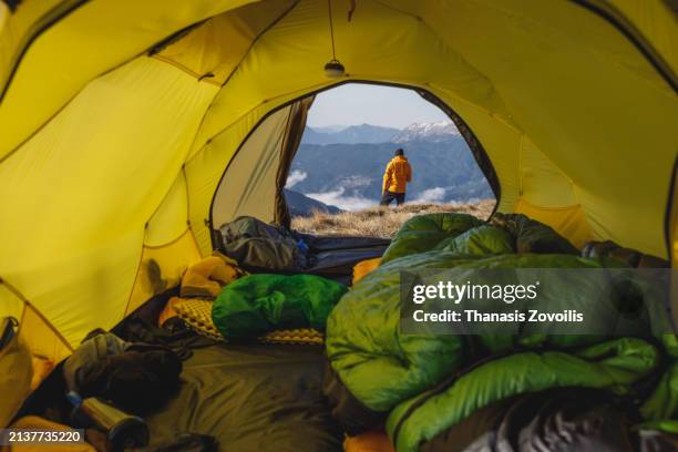 solo trekker enjoys majestic mountain view at sunrise from yellow tent - vacaciones en la nieve fotografías e imágenes de stock