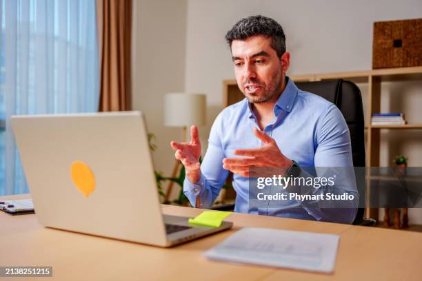 businessman having online virtual meeting call on laptop looking at screen sitting at table in co-working creative office, professional manager talking to employees - middle eastern male on phone isolated stock pictures, royalty-free photos & images