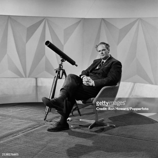 English astronomer, broadcaster and television presenter Patrick Moore seated with a telescope in a studio in London, circa 1970. Patrick Mooore is...