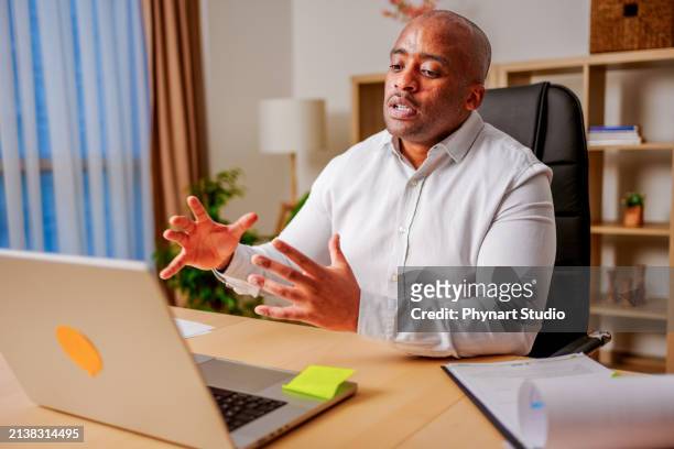 businessman having online virtual meeting call on laptop looking at screen sitting at table in co-working creative office, professional manager talking to employees - middle eastern male on phone isolated stock pictures, royalty-free photos & images