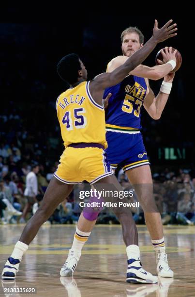 Mark Eaton, Center for the Utah Jazz looks on as he holds up play challenged by AC Green, Power Forward and Small Forward for the Los Angeles Lakers...